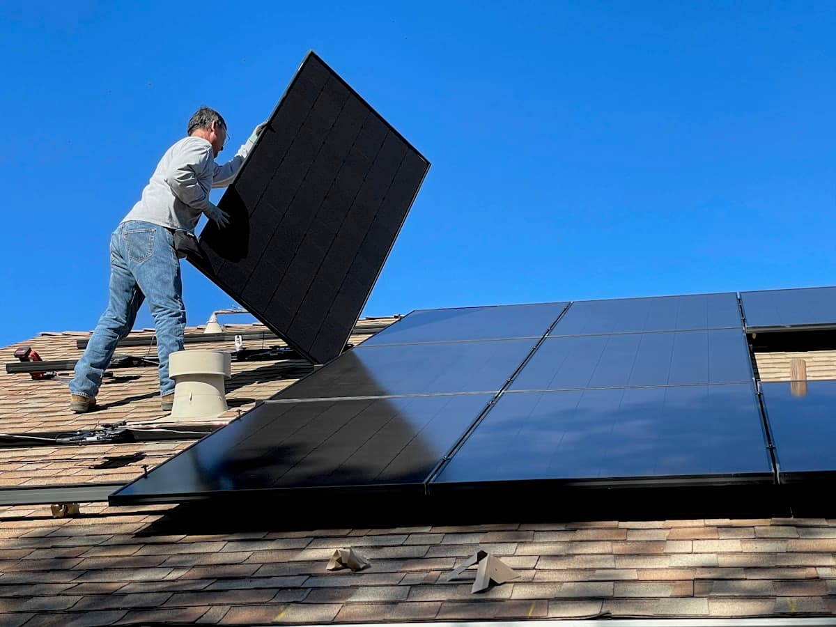 Installer fitting a solar panel on a roof